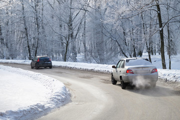 two cars driving on a curved road in winter