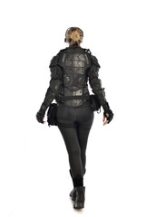 Fototapeta premium full length portrait of female soldier wearing black tactical armour facing away from camera, isolated on white studio background.