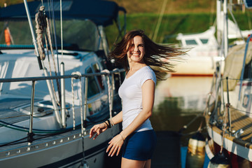 young beautiful girl is smiling at the camera on the background of summer yachts