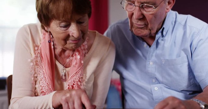 4k, Old couple browsing the internet on their digital touchscreen tablet.