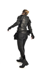 full length portrait of female  soldier wearing black  tactical armour  facing away from camera, isolated on white studio background.