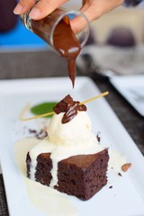 Brownie cake with cocoa cream on white dish in coffee shop.