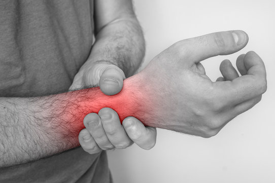 Man with wrist pain is holding his aching hand