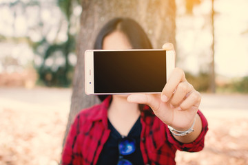 Enjoying moment woman using smartphone sitting under the big tree on park ,Relax time on holiday concept ,color of vintage