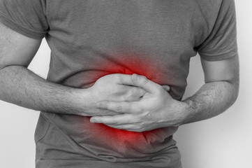 Man with stomach pain is holding his aching belly