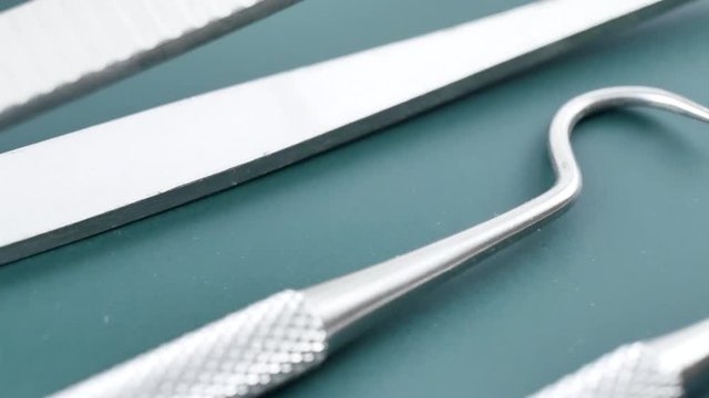 Medical dental instruments on green surface: dentist mirror, forceps curved, explorer curved, dental explorer angular and explorer curved with chip, right. Dental Hygiene and Health conceptual image