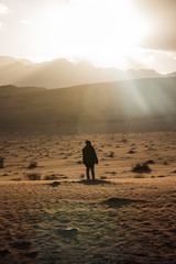 Fototapeta na wymiar Silhouette of a girl who watches the sunset in desert in Jordan