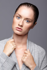 Beauty portrait of young woman in gray dress. Brunette girl with bright blue eyes and day female makeup