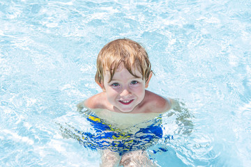 Fototapeta na wymiar Smiling preschool boy in a pool