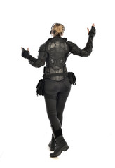 full length portrait of female  soldier wearing black  tactical armour  facing away from camera, isolated on white studio background.