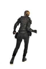 full length portrait of female  soldier wearing black  tactical armour  facing away from camera, isolated on white studio background.