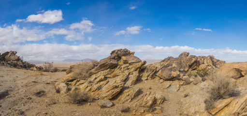 Jagged layers of rock emerge from the soil and sand of a southern desert.