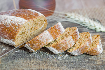 A loaf of rye bread oval shape and cut slices on wooden Board vintage, rustic style, homemade cakes close-up,