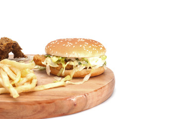 Burger,fries and fried chicken on wooden chopping board isolated over white background.