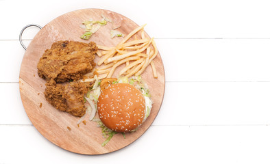 Burger,fries and fried chicken on wooden chopping board isolated over white background.