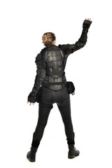full length portrait of female  soldier wearing black  tactical armour  facing away from camera, isolated on white studio background.