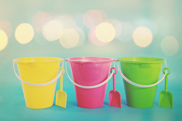  Three sand pail beach toys in a row with shovels