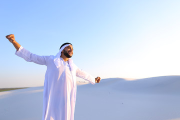 Handsome young Emirate strolls and stretches, spreads hands to sides and rests from city bustle,...