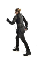 full length portrait of female  soldier wearing black  tactical armour  facing away from camera, isolated on white studio background.