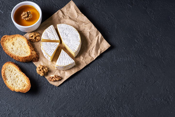 Camembert cheese, toasts, honey and walnuts on a dark background. Flat Lay.