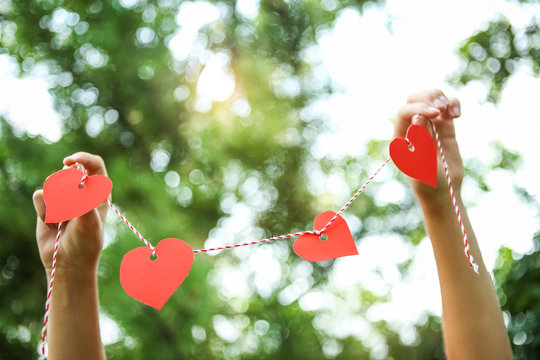 Hands Holding Paper Hearts On A String