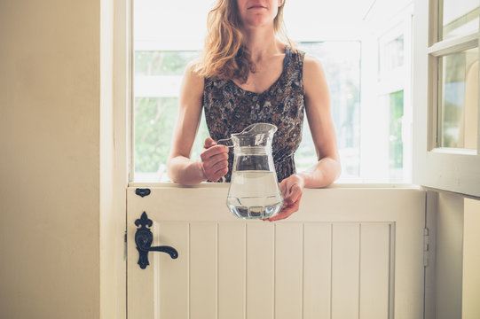 Woman with jug of water by stable door