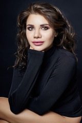 Portrait of sexy woman with black turtleneck sweater with a long collar on a gray background closeup. Beautiful curly hair girl, big beautiful eyes and gorgeous smile