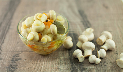 Fresh and pickled mushrooms on wooden background. 