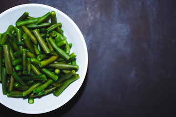 Cooked green beans in white plate on black background, Close up, top view. healthy food, proper nutrition, diet