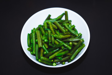 Cooked green beans on black background