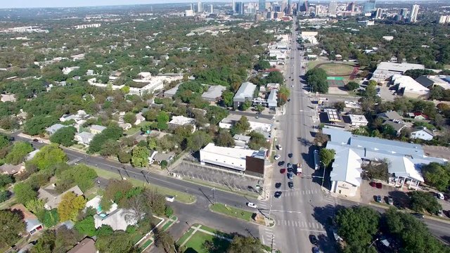 Ascending aerial view of South Congress Avenue in Austin Texas with firetruck passing cars at an intersection