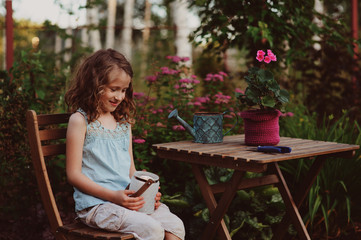 happy romantic child girl dreaming in evening summer garden decorated with candle holder.