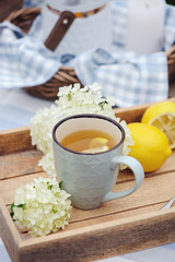 Summer breakfast in beautiful blooming garden. Tea with lemon, hydrangea flowers on wooden table with green background. Summertime and country slow living concept