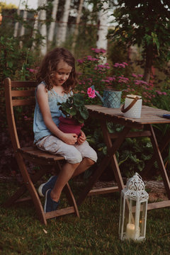 dreamy romantic kid girl relaxing in evening summer garden decorated with lantern and candle holder lights.