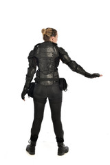 Fototapeta premium full length portrait of female soldier wearing black tactical armour facing away from camera, isolated on white studio background.