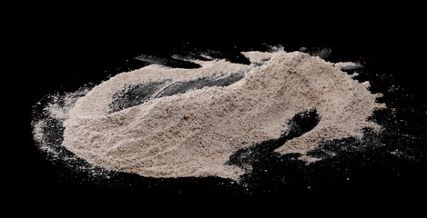 Integral rye flour pile isolated on black background