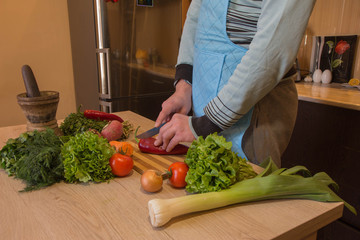 Chef cuts the vegetables into a meal. Preparing dishes, Healthy Food. A Man uses a knife and cooks. Male's hands cooking healthy meal in the kitchen