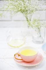 Delicate vintage cups of pink and blue with tea among the white dried flowers of gypsophila. Home interior and still life concept