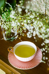 Pink vintage cup with tea on the stand among the white dry flowers of gypsophila. Home interior and still life