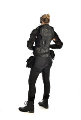 full length portrait of female  soldier wearing black  tactical armour  facing away from camera, isolated on white studio background.