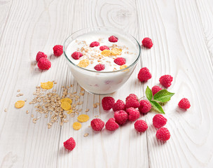 Bowl of homemade yogurt with muesli and fresh raspberry on wooden table. Fresh yogurt. Healthy food concept. High resolution product.