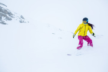 Fototapeta na wymiar Photo of female athlete wearing helmet with developing hair, snowboarding from mountain slope