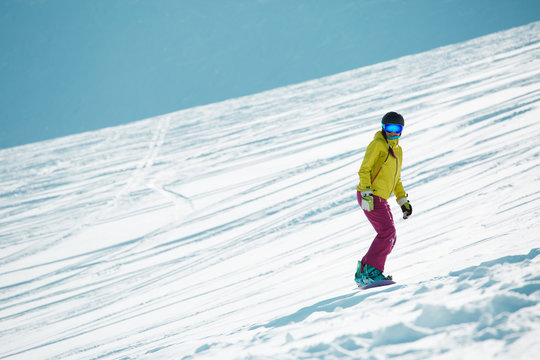 Picture of sports woman wearing helmet and mask, snowboarding from mountain slope