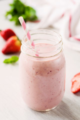 Pink strawberry smoothie bottle with drinking straw on grey background
