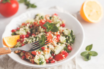 Tabbouleh salad with tomato, cucumber, couscous, mint and pomegranate. Vegan Healthy Food Concept. Traditional middle eastern or arab dish.