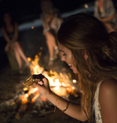 Girl eating a smore by a campfire