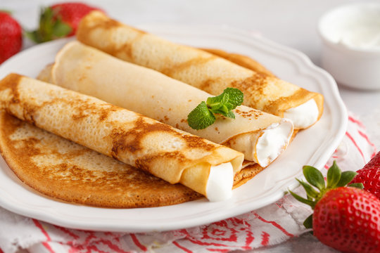 Thin hot pancakes with cottage cheese and strawberries. Healthy traditional breakfast concept.