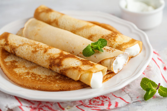 Thin hot pancakes with cottage cheese and strawberries. Healthy traditional breakfast concept.