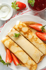 Thin hot pancakes with sour cream, jam and strawberries. Top view, copy space. Healthy traditional breakfast concept.