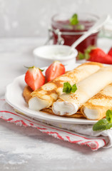 Thin hot pancakes with cottage cheese, jam and strawberries. Breakfast background.